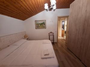 a bedroom with a large white bed and a wooden ceiling at Apartment Pineta Alben 2 in Serina