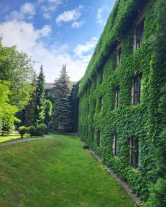 an ivy covered wall of a building with a yard at Booking Hotel & Spa in Krakow