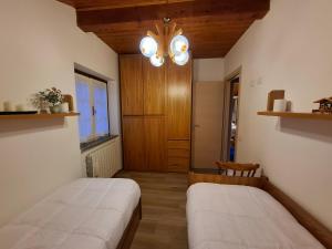a bedroom with two beds and a chandelier at Apartment Pineta Alben 2 in Serina +2 photos