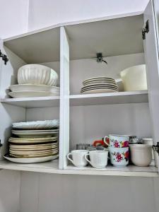 a white cabinet filled with plates and cups and dishes at Casa no centro de Poços de Caldas in Poços de Caldas