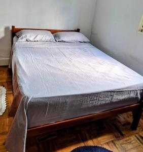 a bed with a wooden frame with a white mattress at Casa no centro de Poços de Caldas in Poços de Caldas