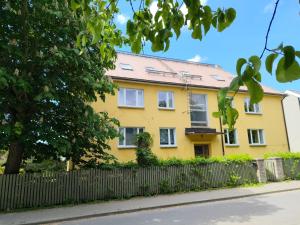 a yellow house with a fence in front of it at Turu 6, Quiet Central Apartment in Haapsalu