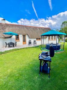 a house with a yard with a table and umbrellas at Chaumière cosy avec SPA Baie de somme in Abbeville