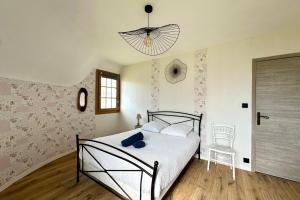 a bedroom with a bed and a chair and a chandelier at Chaumière cosy avec SPA Baie de somme in Abbeville
