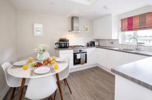 a white kitchen with a table with fruit on it at Lucy's Lodge- Most Stylish Apartment On Vibrant Bishy Road with Free Parking in York +10 photos