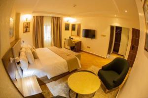 a hotel room with a large bed and a chair at CARITAS HOTEL AND suite in Araromi +4 photos