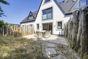 a white house with chairs and a fence at Strandwächter in Hörnum