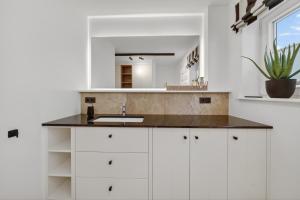 a white kitchen with a sink and a mirror at Strandwächter in Hörnum +58 photos