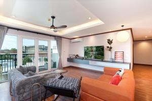 a living room with an orange couch and chairs at Capitel Ekkamai Hotel in Sathani Khlong Tan