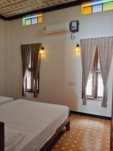 a bedroom with two beds and windows in it at Vriksha Heritage Farm Stays in Sethumadai