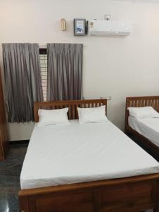 a bedroom with two beds with white sheets and a window at Vriksha Heritage Farm Stays in Sethumadai +6 photos