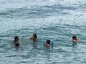 drie vrouwen en twee kinderen zwemmen in het water bij Caixa D'aço Residence in Porto Belo