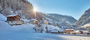 a village covered in snow with the sun in the background at Haus Alpenblick - Silvretta Card Premium INKLUSIVE in See