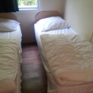 two unmade beds in a small room with a window at VZ779 Stacaravan in Wemeldinge in Wemeldinge +8 photos