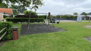 a park with a swing set in the grass at VZ779 Stacaravan in Wemeldinge in Wemeldinge