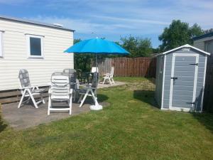 a patio with a table and chairs and an umbrella at VZ779 Stacaravan in Wemeldinge in Wemeldinge