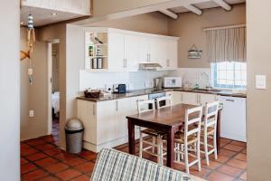 a kitchen with white cabinets and a wooden table at Duifie in Paternoster