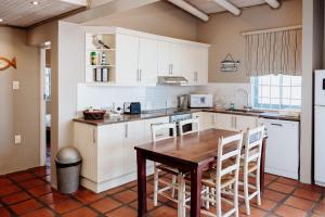a kitchen with white cabinets and a wooden table at Duifie in Paternoster +17 photos