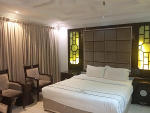 a bedroom with a large bed and a chair at جولدن نيو الدار للشقق المخدومة in Jazan