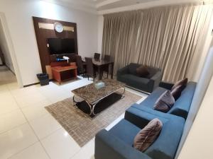 a living room with two blue couches and a table at جولدن نيو الدار للشقق المخدومة in Jazan