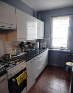 a kitchen with white cabinets and a stove top oven at Sleep & Chill in Leszno