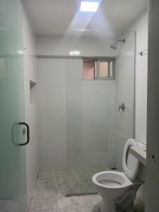 a white bathroom with a toilet and a shower at Hostal Center A in Santa Cruz de la Sierra