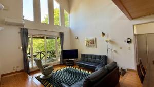 a living room with a couch and a television at Garden Villa Minamiaso in Minami Aso
