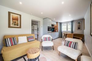 a living room with a couch and chairs and a kitchen at Alpine ski apartment - Petit Chatel in Châtel