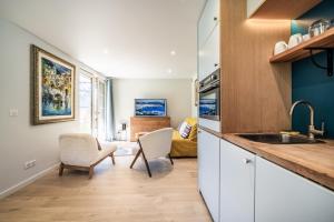 a kitchen with a sink and two chairs and a living room at Alpine ski apartment - Petit Chatel in Châtel +13 photos