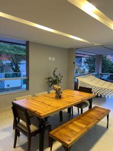 a dining room with a wooden table and benches at Apartamento amplo João VI in Muriaé
