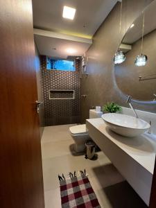 a bathroom with a sink and a toilet and a mirror at Apartamento amplo João VI in Muriaé