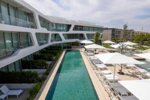 a swimming pool in front of a building with white umbrellas at The YACHT - By Fattal Limited Edition in Herzliya B