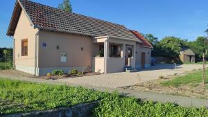 a small white house with a driveway at Apartman Noemi in Apševci