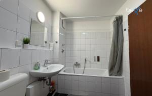 a white bathroom with a sink and a tub at BEGE APARTMENTS HomeAway in Marl +5 photos