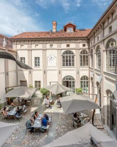 people sitting at tables in front of a building with umbrellas at Palazzo Righini in Fossano