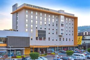 a building with cars parked in a parking lot at City Express Plus by Marriott Guadalajara Palomar in Guadalajara