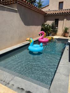 a swimming pool with three inflatable ducks in the water at Studio piscine in Bouc-Bel-Air