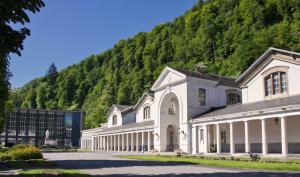 a large white building with a mountain in the background at Chez Mina in Saint-Béat
