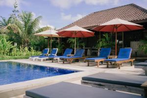 a group of chairs and umbrellas next to a pool at Uluwatu Jungle Villa in Uluwatu