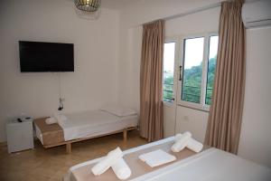 ein Hotelzimmer mit zwei Betten und einem Flachbildfernseher in der Unterkunft Deve Mar Hotel in Borsh