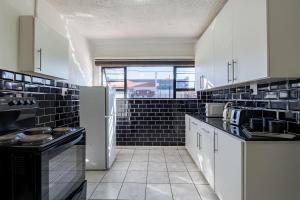 a kitchen with white appliances and black tiles at Safi Self-catering Suite 2 in Bunkers Hill +10 photos