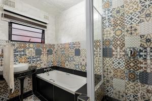 a bathroom with a tub and a sink and tiles at Safi Self-catering Suite 2 in Bunkers Hill