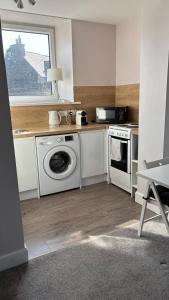 a kitchen with a washing machine and a window at Scott Street Modern Flat in Galashiels