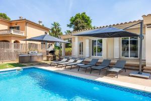 a swimming pool with chairs and umbrellas next to a house at Villa Ramón in Palma de Mallorca