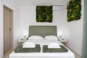 a bedroom with a white bed with plants on the wall at Apartments Milas in Okrug Gornji