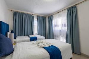 two beds in a room with blue curtains at Safi Self-Catering Suite 1 in Bunkers Hill