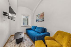 a living room with a blue couch and a chair at easy-flat Hauptplatz - City Center Apartments with a Kitchen in Villach