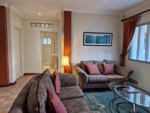 a living room with a couch and a glass table at Villa Sardinia Guest House in Midrand