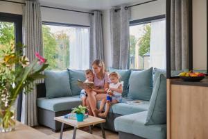 a woman and two children sitting on a couch at Siblu Camping Meerwijck in Kropswolde