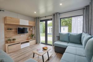 a living room with a blue couch and a tv at Siblu Camping Meerwijck in Kropswolde +25 photos